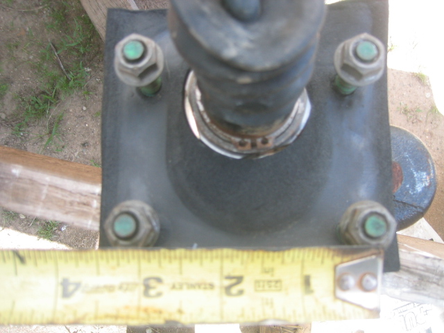 Brake booster mounting bracket with four bolts and a measuring tape showing 3 inches