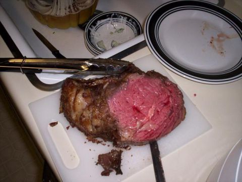 1989 Ford Bronco - A prime rib roast, partially carved, sits on a cutting board next to used plates and serving tongs.