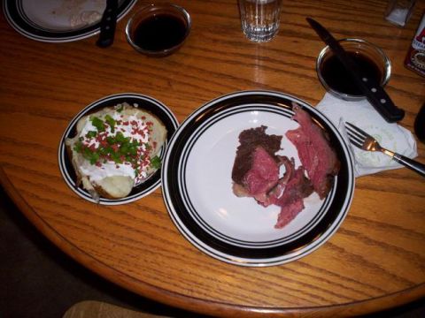 1989 Ford Bronco - A meal of sliced steak and a baked potato topped with sour cream and bacon bits is served on a wooden table.