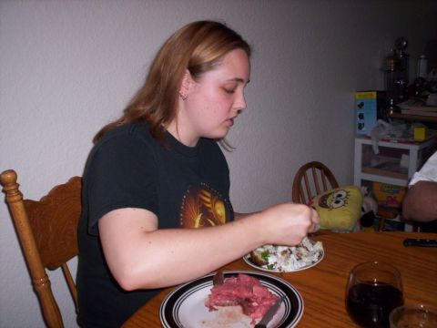 1989 Ford Bronco - A woman is seated at a table, eating a meal that includes sliced meat and a salad.