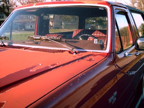 1986 Ford Bronco - The cracked dashboard and faded red paint are visible on this SUV, with a license plate reading 3 07 in the passenger window.