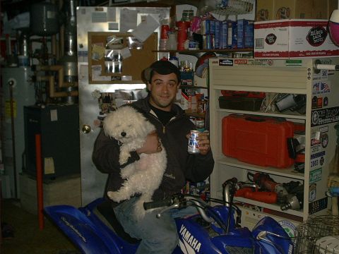 2005 Ford Excursion - Man with dog on ATV in garage, with shelves of tools and supplies in background.