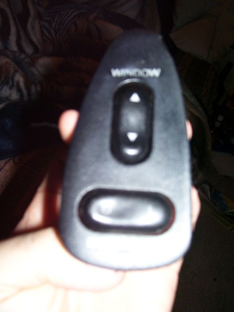 1993 Mazda MX-6 - A hand holds a car's power window control switch. The text 'WINDOW' is visible above the buttons.