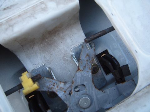 1997 Ford Ranger - Close-up view of a tailgate latch mechanism, showing rusted metal components and a yellow plastic clip.