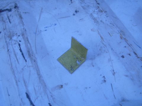 1997 Ford Ranger - A single yellow metal L-bracket is shown on a textured blue surface.