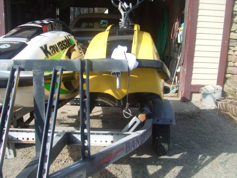 1998 Kawasaki JH1100-A4 1100 ZXi - Two jet skis are seen on a trailer, one yellow and one white with green accents, parked in a garage.