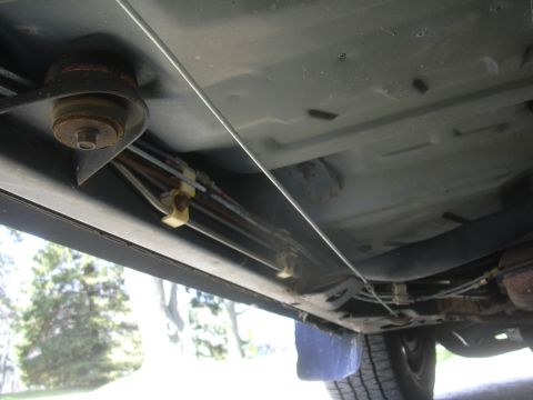 1996 Ford Crown Victoria - The underbody of a vehicle reveals brake and fuel lines secured by clips along the frame.