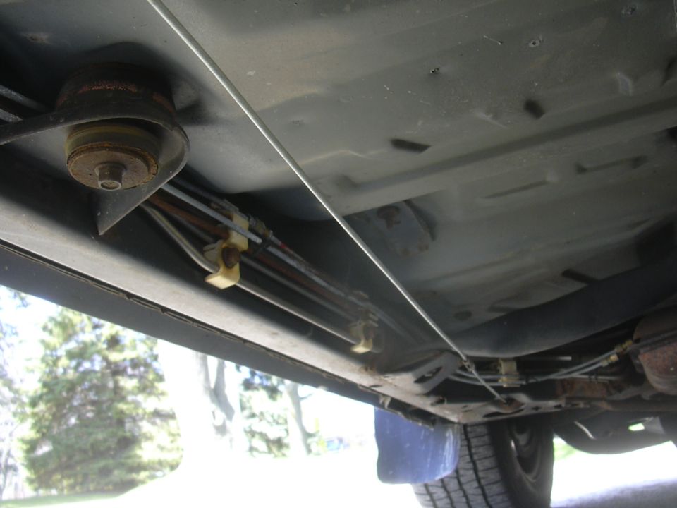 Underside view of vehicle showing brake lines and fuel lines running along the frame rail