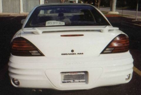 1986 Ford LTD Crown Victoria - Rear view of a white Pontiac Grand Am, its distinctive taillights and spoiler.