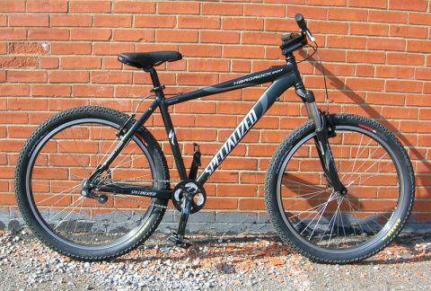 1997 Ford Probe - A black Specialized Hardrock mountain bike is shown in profile against a brick wall.