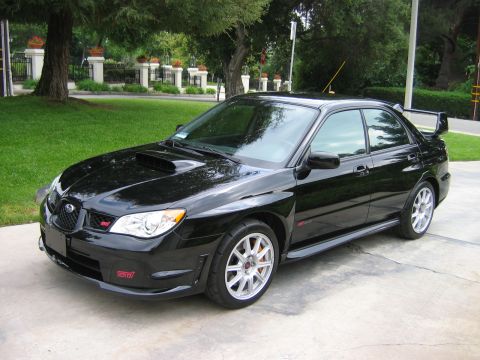 2007 Subaru Impreza - A black Subaru Impreza WRX STI sedan is parked on a concrete driveway with a grassy lawn and decorative pillars in the background.