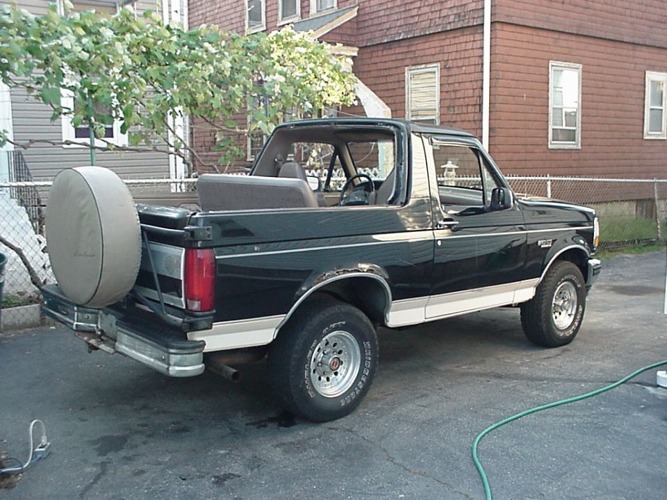 Black Ford Bronco with top off and covered swing-away spare, rear three-quarter view