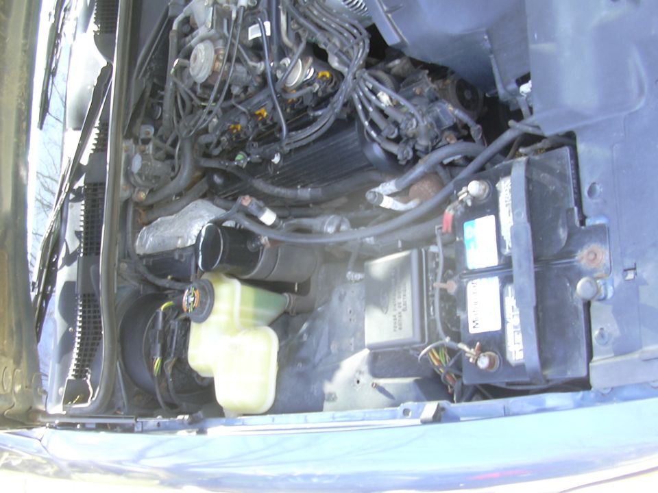 Engine bay showing battery, coolant reservoir, and engine components
