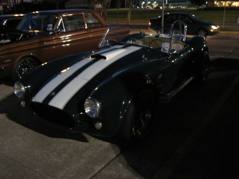 2000 Ford Crown Victoria - A classic dark green convertible with white racing stripes is parked outdoors at night.