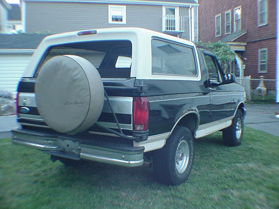 Rear view of a black and white Ford Bronco with a spare tire on the back