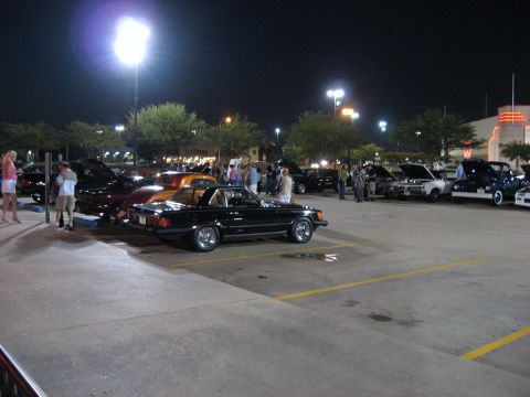 2000 Ford Crown Victoria - Cars gathered in a parking lot at night, with several people milling about.