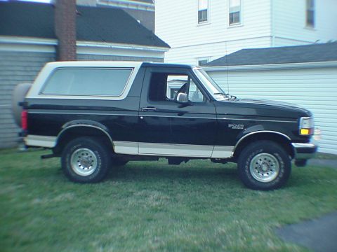 1993 Ford Bronco - This black and white Ford Bronco SUV is parked on a grassy lawn in front of a house and garage.