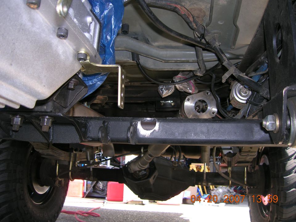Underside view of a vehicle's drivetrain, showing the transmission, driveshaft, and rear axle assembly