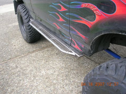 1996 Ford Bronco - A black 1996 Ford Bronco is shown with custom flame decals and running boards.