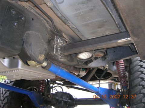 1996 Ford Bronco - Close-up view of the undercarriage, highlighting custom blue suspension parts and heavy-duty tires on a modified SUV.