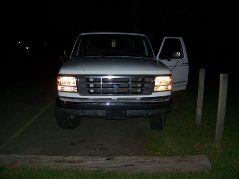 1995 Ford Bronco - This 1995 Ford Bronco is seen from the front with its headlights illuminated and the driver's door ajar.