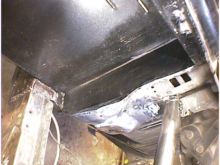 Welded seam joining a black firewall panel to the frame rail, viewed from underneath