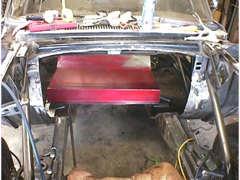 1960 Ford Falcon - The engine bay of a car is shown with a red component installed and various tools on the dashboard.