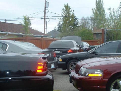 2000 Ford Crown Victoria - A red 2000 Ford Crown Victoria is parked in a lot with other vehicles, showing its front corner and headlight detail.
