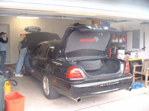 2000 Ford Crown Victoria - A black Ford Marauder is parked in a garage with its hood and trunk open, revealing the interior and spare tire compartment.