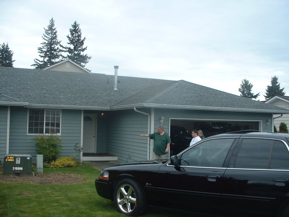 Black full-size sedan with chrome wheels parked in a suburban driveway