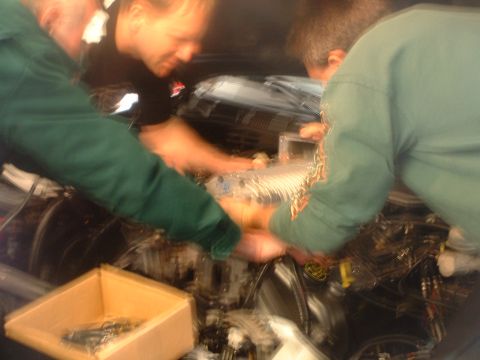 2000 Ford Crown Victoria - Mechanics work on a supercharger installation in an engine bay. The registry claims it is a 2000 Ford Crown Victoria, but this is unconfirm…