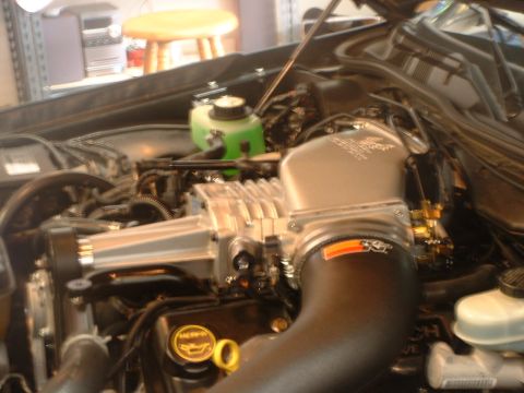 2000 Ford Crown Victoria - Close-up of a modified engine bay, showing a prominent supercharger and intake system.