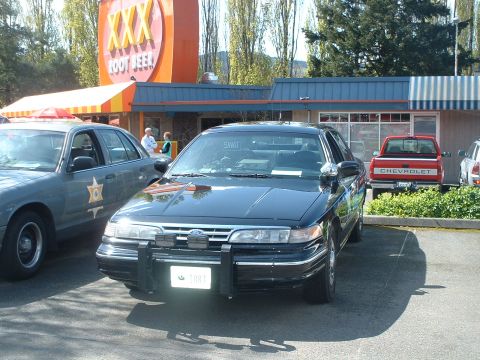 2000 Ford Crown Victoria - Police car with push bar and SWAT sign in window, parked near a XXX Root Beer stand.