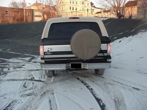1993 Ford Bronco - Rear view of a 1993 Ford Bronco parked in the snow, showing its spare tire cover.