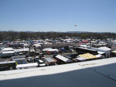 1991 Ford LTD Crown Victoria - A wide view of an outdoor market with numerous tents and vehicles spread across the landscape under a bright blue sky.