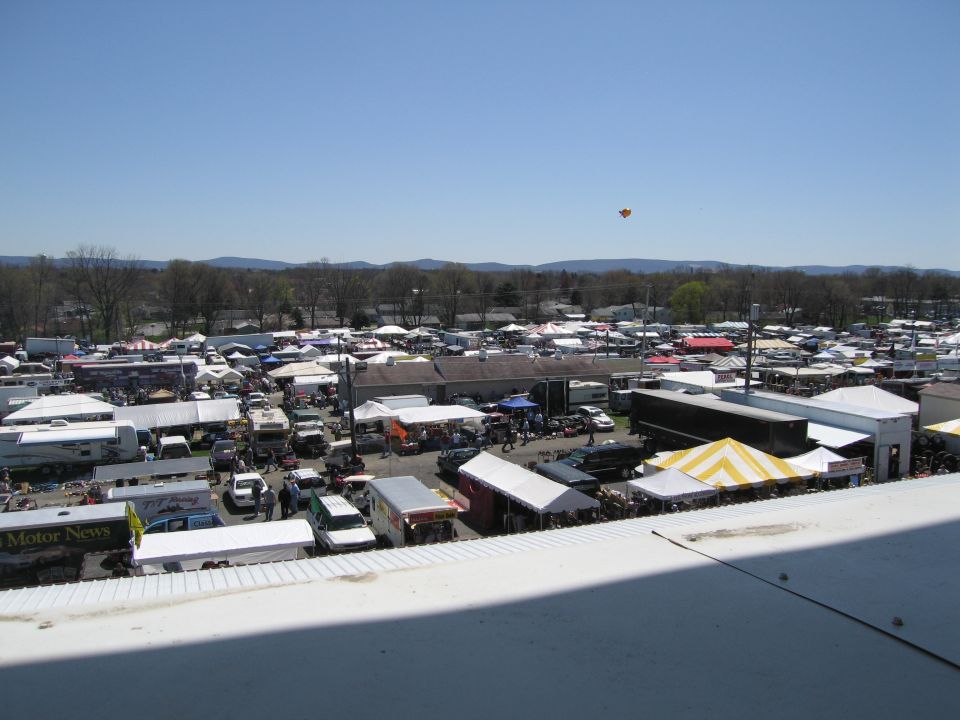 Outdoor market scene with many tents and vehicles under a clear blue sky