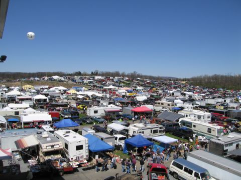1991 Ford LTD Crown Victoria - A vast outdoor gathering of vehicles and vendors under a bright blue sky, suggesting a car show or swap meet.