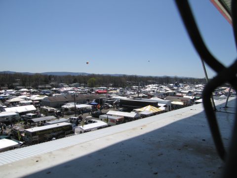 1991 Ford LTD Crown Victoria - A wide view of an outdoor market filled with tents and vehicles on a sunny day.