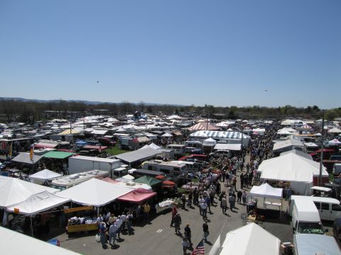 1991 Ford LTD Crown Victoria - A wide view of a bustling outdoor market filled with numerous tents, vendors, and vehicles under a bright, clear sky.