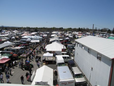 1991 Ford LTD Crown Victoria - A busy outdoor market scene with numerous tents and vehicles spread across a large area.