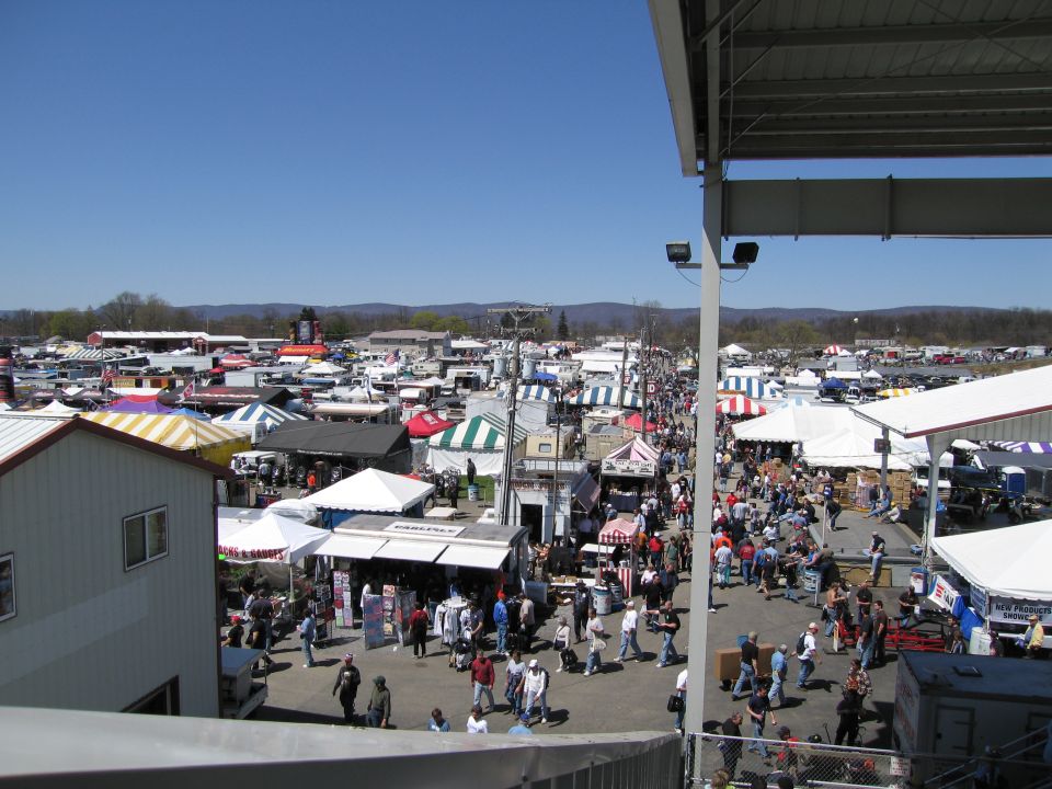 Outdoor market scene with many tents, stalls, and people browsing under a clear blue sky
