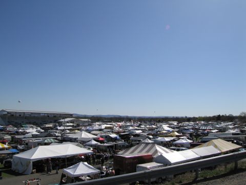 1991 Ford LTD Crown Victoria - A wide view of a bustling outdoor market filled with tents and vehicles on a sunny day.