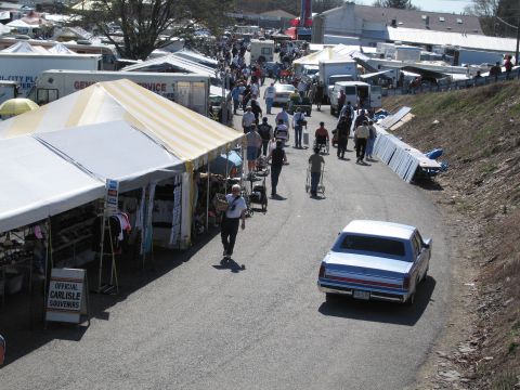 1991 Ford LTD Crown Victoria - A blue sedan drives through a busy outdoor market with many tents and people.