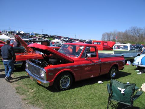 1991 Ford LTD Crown Victoria - A red pickup truck, likely from the early 1970s, is displayed with its hood open at a car show, surrounded by other vehicles.