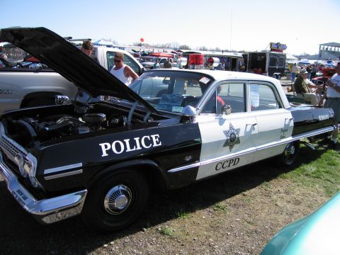 1991 Ford LTD Crown Victoria - This two-tone police car, likely a 1963 model, is displayed with its hood open, revealing the engine compartment.