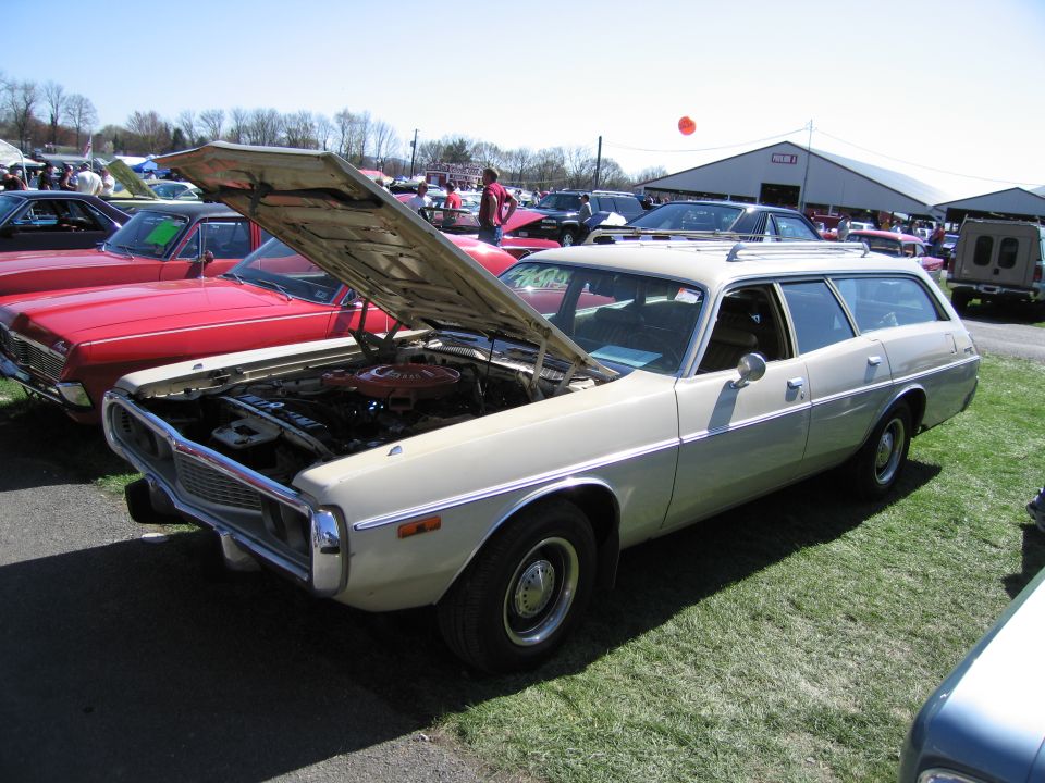 Beige station wagon with hood open, parked on grass next to a red car