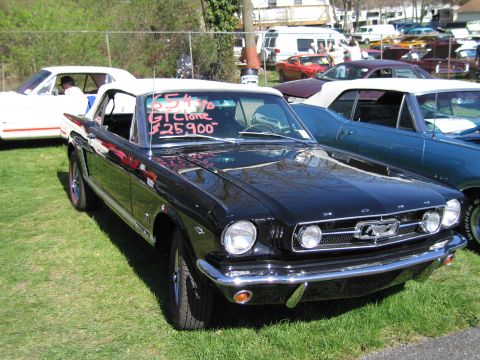 1991 Ford LTD Crown Victoria - A black 1965 Ford Mustang convertible is displayed on a grassy lot with other vehicles.