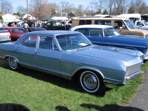 1991 Ford LTD Crown Victoria - A light blue sedan is parked on a grassy field with other vehicles in the background.