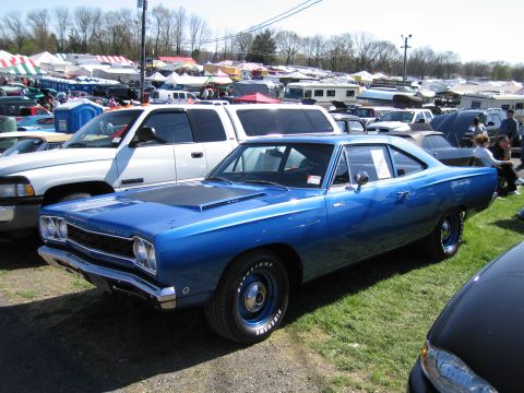 1991 Ford LTD Crown Victoria - A blue 1969 Plymouth Road Runner is parked at an outdoor event with tents and other cars visible.