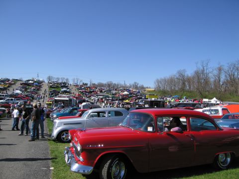 1991 Ford LTD Crown Victoria - A large gathering of cars is displayed on a sunny day, with a red Chevrolet in the foreground.